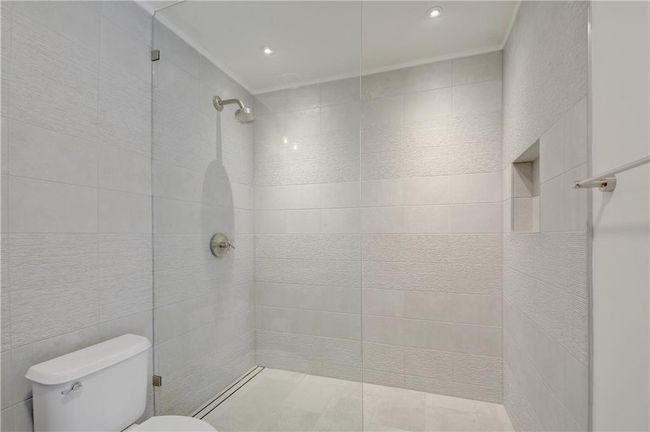 Full bathroom with tile walls, toilet, and a tile shower | Image 17
