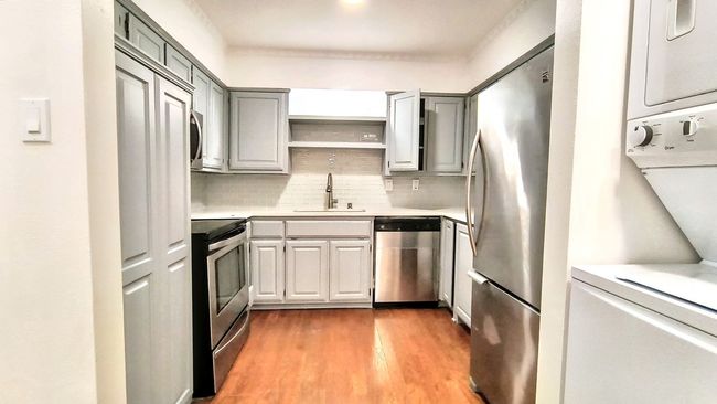 Kitchen with gray cabinets, appliances with stainless steel finishes, sink, decorative backsplash, and light wood-type flooring | Image 13
