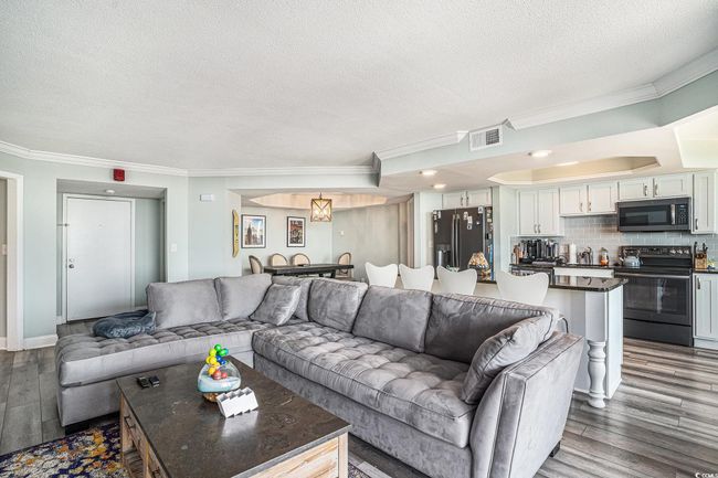 Living area featuring dark wood-type flooring, a textured ceiling, and ornamental molding | Image 8