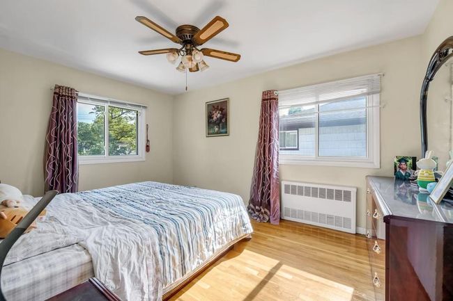 Bedroom with radiator heating unit, light wood finished floors, and ceiling fan | Image 11