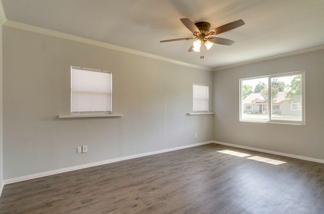 Spare room featuring dark wood-style floors, ceiling fan, and crown molding | Image 17