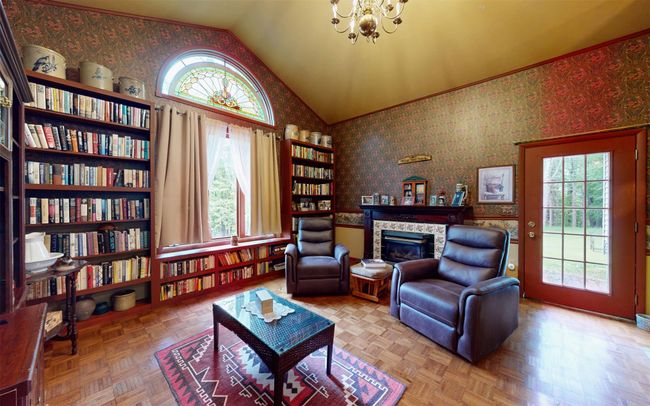 Sitting room with a glass covered fireplace, lofted ceiling, wallpapered walls, and a chandelier | Image 23
