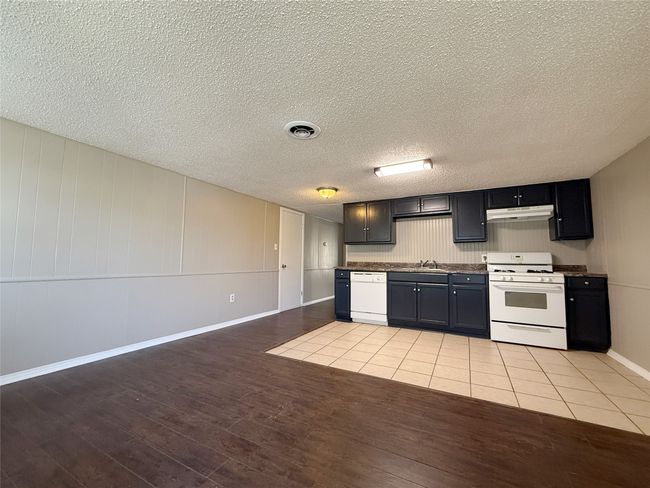 Kitchen featuring visible vents, white appliances, under cabinet range hood, a sink, and light wood-type flooring | Image 5
