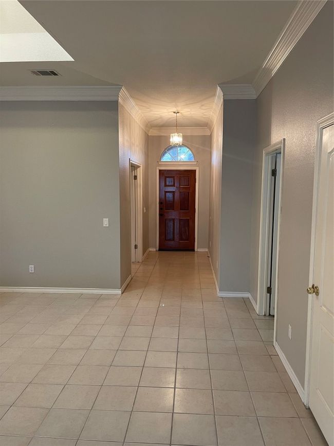 Hallway featuring ornamental molding, light tile patterned floors, and a chandelier | Image 20