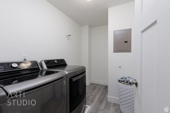Laundry room featuring laundry area, light wood-style flooring, separate washer and dryer, electric panel, and baseboards | Image 17