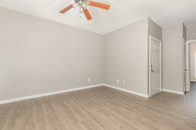 Spare room featuring light wood finished floors, ceiling fan, baseboards, and a textured ceiling | Image 9