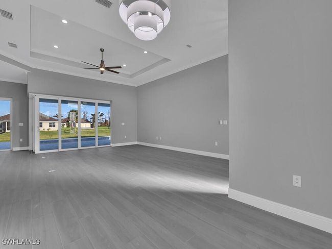 Spare room featuring a raised ceiling, a ceiling fan, crown molding, recessed lighting, and wood finished floors | Image 17