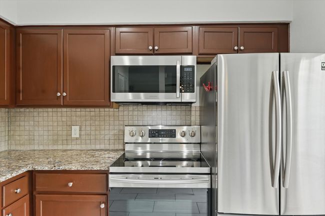 Kitchen featuring appliances with stainless steel finishes, backsplash, and light stone counters | Image 13