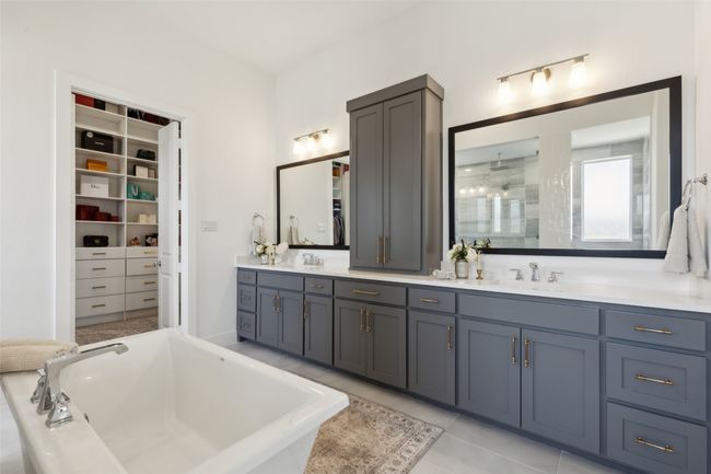 Bathroom featuring a soaking tub, double vanity, a walk in closet, and tile patterned floors | Image 17