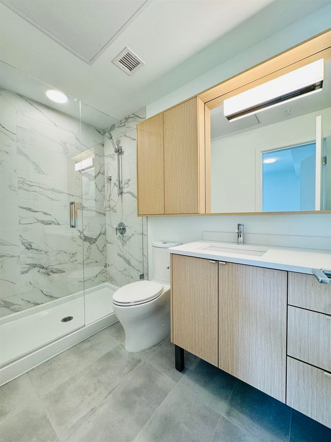 Full bathroom featuring toilet, visible vents, a marble finish shower, and vanity | Image 11