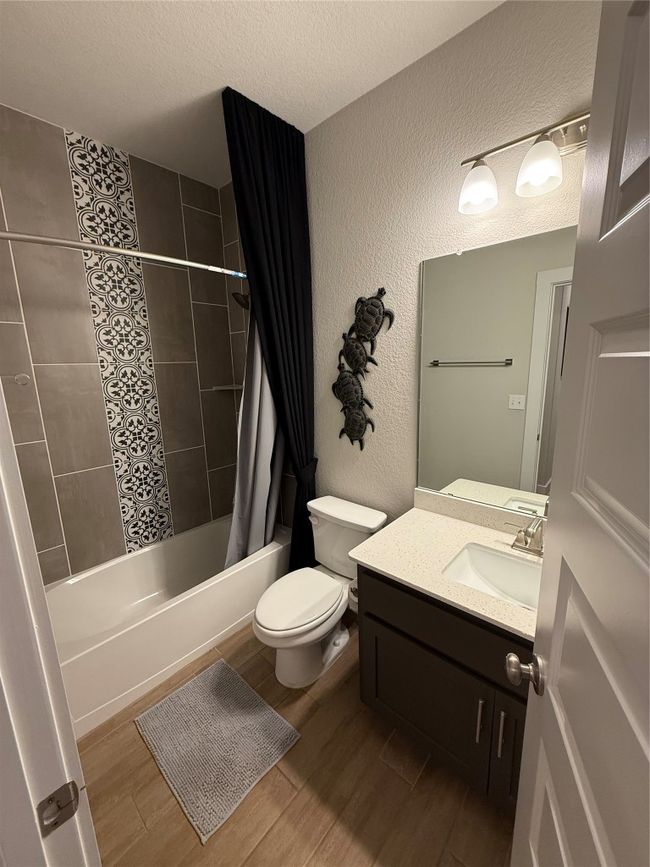 Full bath with vanity, shower / bath combination with curtain, wood finished floors, toilet, and a textured wall | Image 6