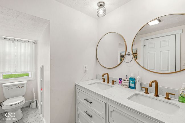 bathroom with double vanity, tile patterned floors, toilet, and a textured ceiling | Image 22