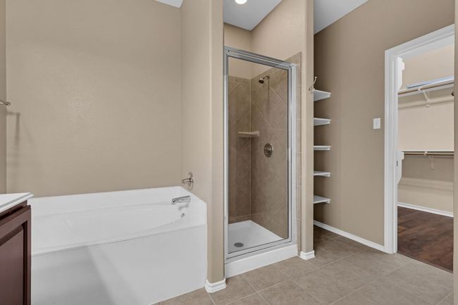 The private primary suite boasts tall ceilings, a ceiling fan, and a luxurious en-suite bathroom complete with a double vanity, garden soaking tub, separate shower, and a large walk-in closet. | Image 18