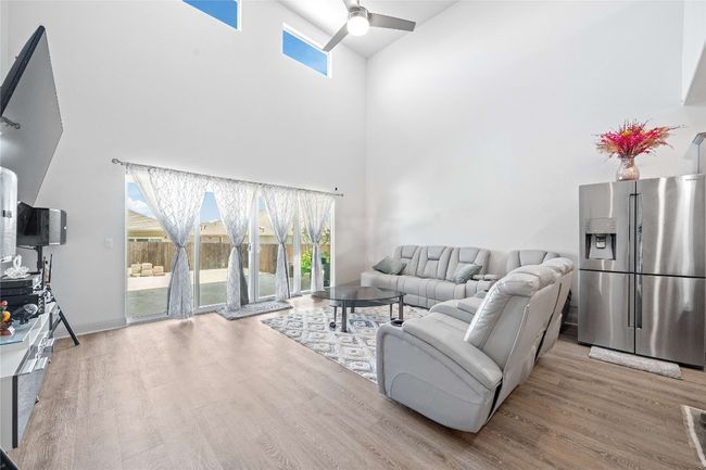 Living area with wood finished floors, a ceiling fan, and a healthy amount of sunlight | Image 14