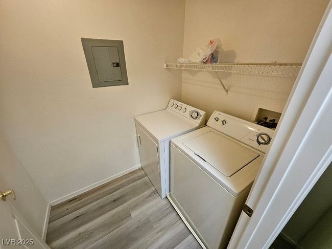 Clothes washing area featuring light wood finished floors, electric panel, washer and dryer, and laundry area | Image 25