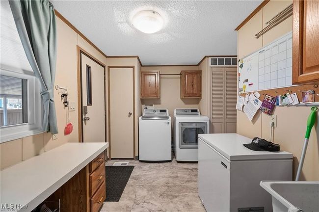 Laundry room with cabinet space, washer and clothes dryer, a textured ceiling, and ornamental molding | Image 20