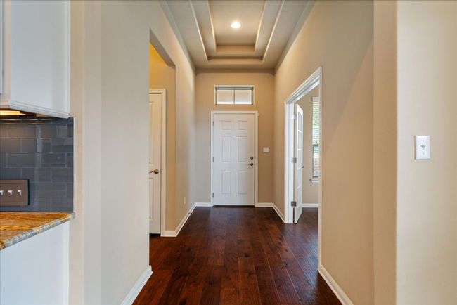 The foyer features wood floors, a raised ceiling, and recessed lighting. | Image 6