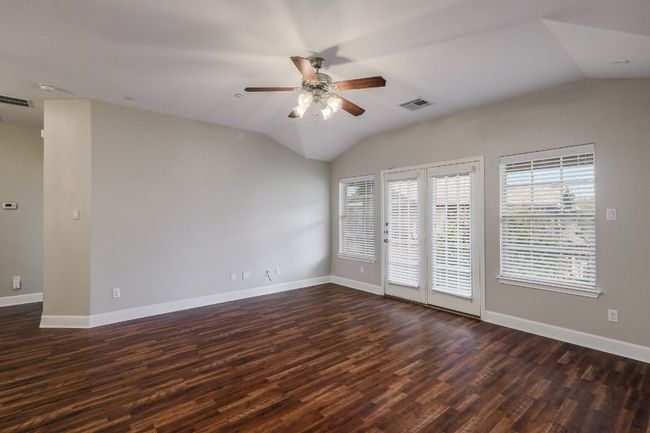 Family room with dark laminate wood floors. French doors leading out to the balcony | Image 5