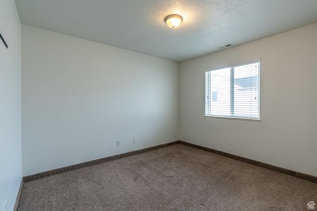 Carpeted spare room featuring baseboards, a textured ceiling, and visible vents | Image 12
