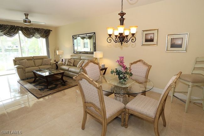 Tiled dining room with ceiling fan with notable chandelier | Image 7