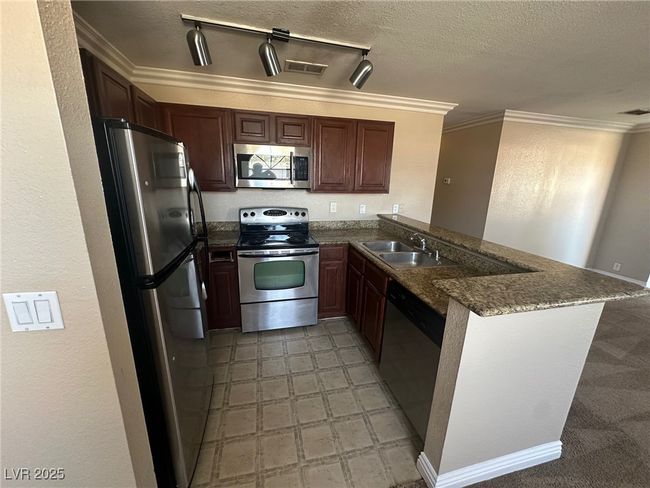 Kitchen with appliances with stainless steel finishes, a peninsula, ornamental molding, and a sink | Image 8