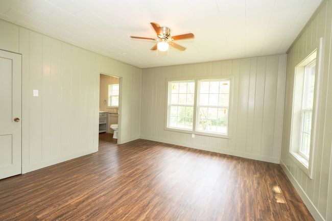 Empty room with dark wood finished floors, ceiling fan, plenty of natural light, and a decorative wall | Image 25