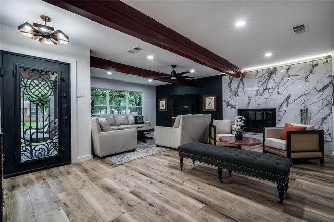 Living area featuring beamed ceiling, wood finished floors, a ceiling fan, a fireplace, and recessed lighting | Image 5