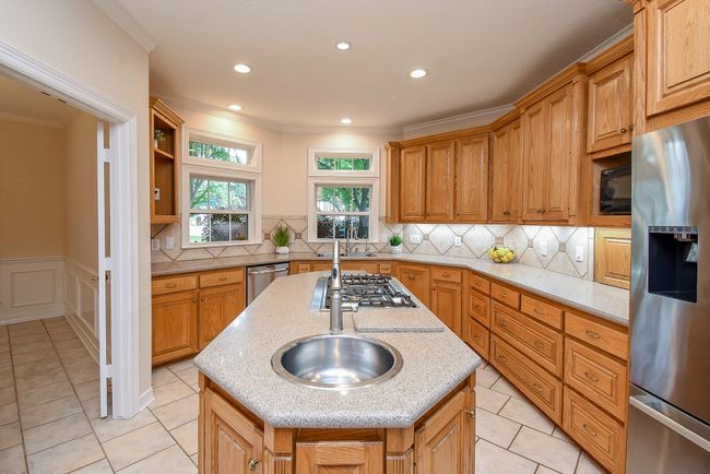 Modern island kitchen with stainless steel appliances and a convenient vegetable sink. | Image 19