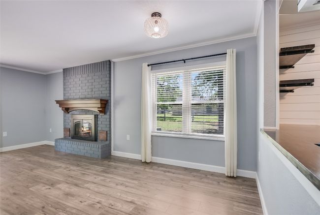 Unfurnished living room with ornamental molding, wood finished floors, and a fireplace | Image 14