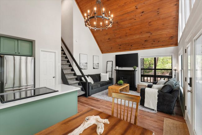 Living area with high vaulted ceiling, a notable chandelier, stairs, and light wood-style flooring | Image 26