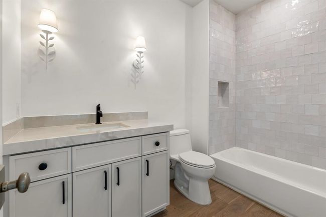 The fourth full bathroom is elegantly neutral with white counter tops and tiles standing out against the wood floors. | Image 32