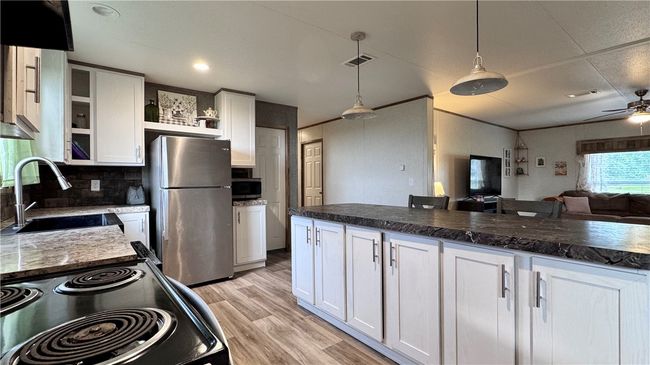 Kitchen featuring open shelves, stainless steel appliances, white cabinets, a ceiling fan, and ornamental molding | Image 11