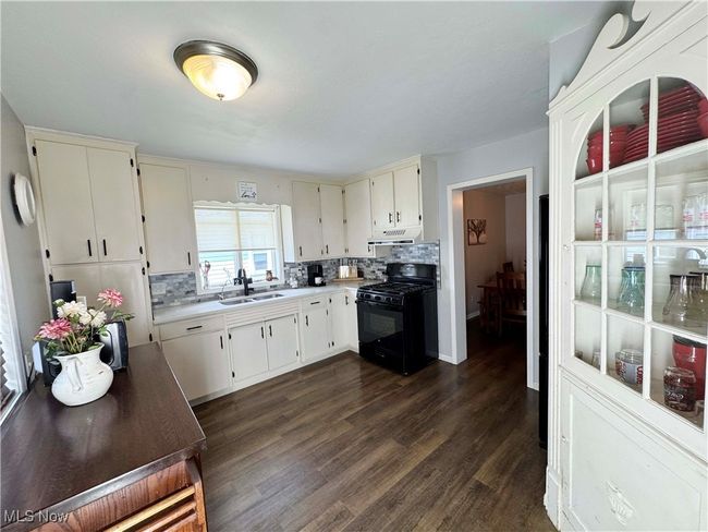 Kitchen featuring black range with gas cooktop, tasteful backsplash, dark wood-style flooring, and light countertops | Image 14