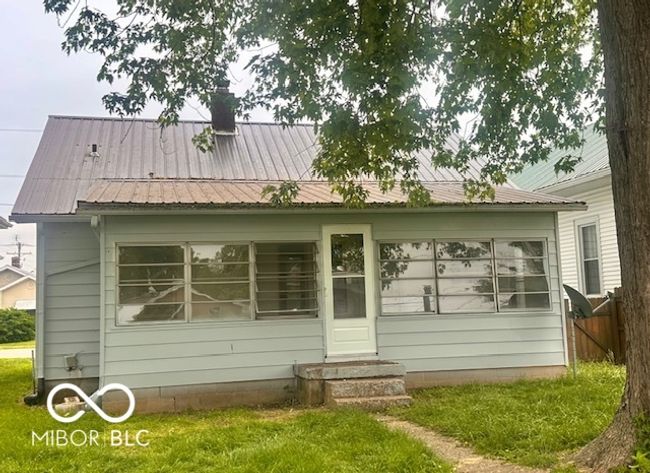 back of property featuring entry steps, a chimney, a lawn, and metal roof | Image 22