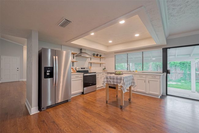 Nicely updated kitchen is just around the corner from the dining room complete with stainless steel appliances, herringbone backsplash and quartz countertops | Image 8