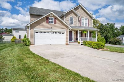 View of front of home featuring a garage, a front yard, and a porch | Image 1