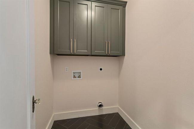The in-house utility room provides ample space for a full-size washer and dryer, with built-in overhead cabinetry for generous storage. A herringbone tile floor adds a touch of elegance. | Image 34