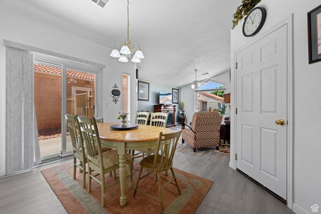 Dining room with lofted ceiling, wood finished floors, and ceiling fan with notable chandelier | Image 8