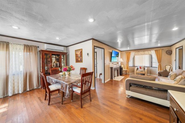 Dining area featuring an AC wall unit, ornamental molding, hardwood / wood-style floors, baseboards, and a fireplace | Image 11