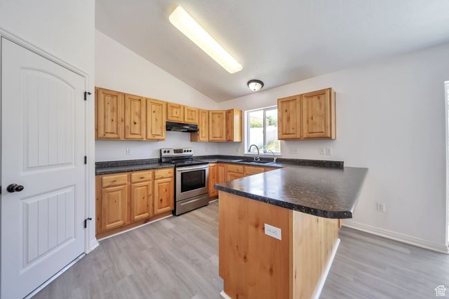 Kitchen featuring stainless steel range with electric stovetop, a sink, vaulted ceiling, and dark countertops | Image 11