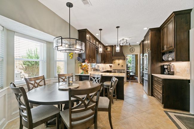 Gourmet kitchen flows seamlessly into a bright breakfast nook with a bay window. | Image 10
