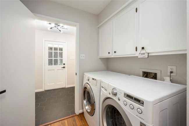 Functional laundry room connected to both the kitchen and back door, equipped with generous cabinetry and shelving for storage. | Image 23