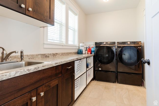 Laundry area featuring independent washer and dryer, light tile patterned floors, and cabinet space | Image 19