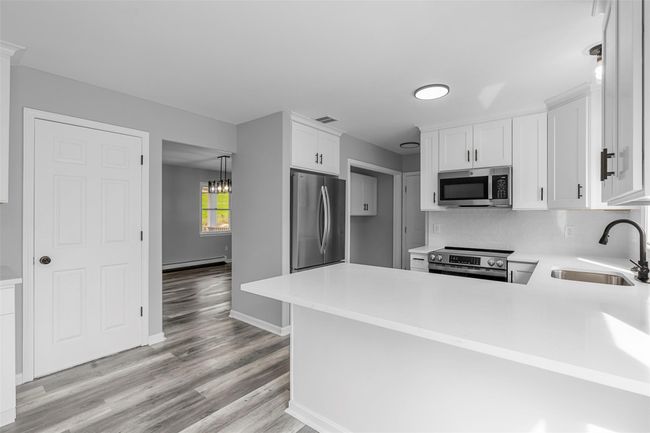 Kitchen with a sink, stainless steel appliances, light wood-style floors, white cabinetry, and light countertops | Image 5