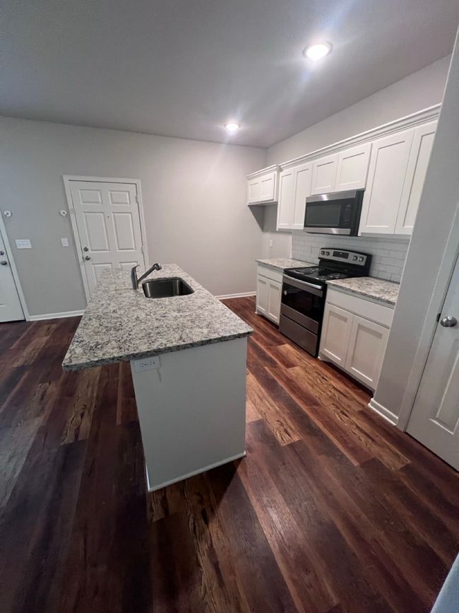 Kitchen featuring appliances with stainless steel finishes, a sink, white cabinetry, tasteful backsplash, and a center island with sink | Image 12