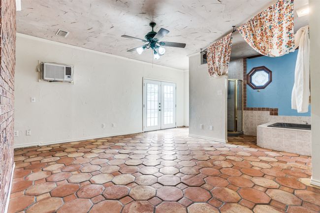 Unfurnished living room featuring a wall mounted air conditioner, a ceiling fan, ornamental molding, and french doors | Image 23