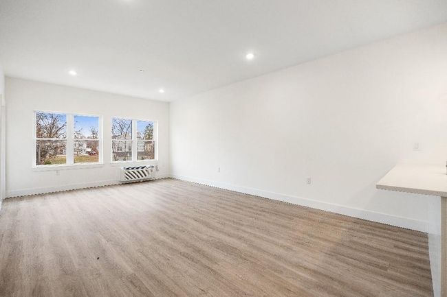 Unfurnished living room with wood finished floors, baseboards, recessed lighting, and a wall mounted air conditioner | Image 35