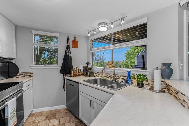 Kitchen featuring dishwasher, a sink, light countertops, baseboards, and stove | Image 8