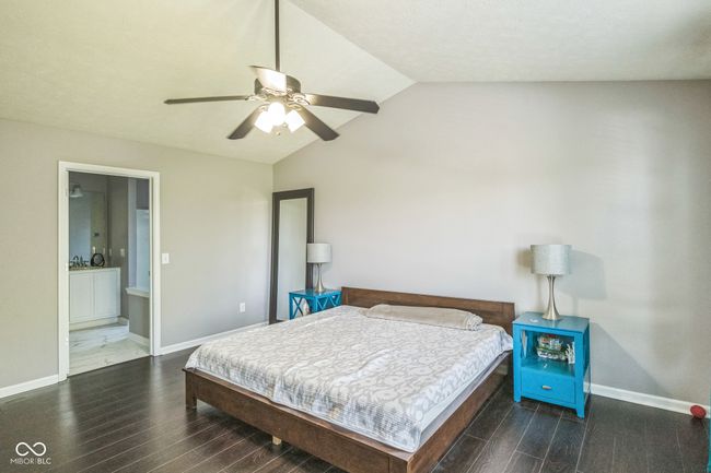 bedroom featuring wood finished floors, lofted ceiling, ensuite bath, and a ceiling fan | Image 24