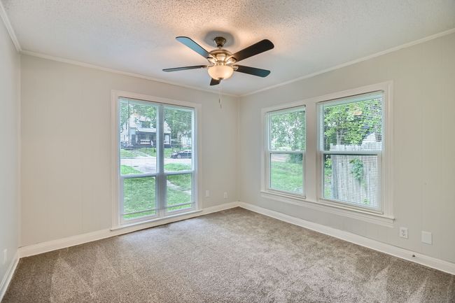 Carpeted spare room featuring baseboards, a ceiling fan, a textured ceiling, and crown molding | Image 21